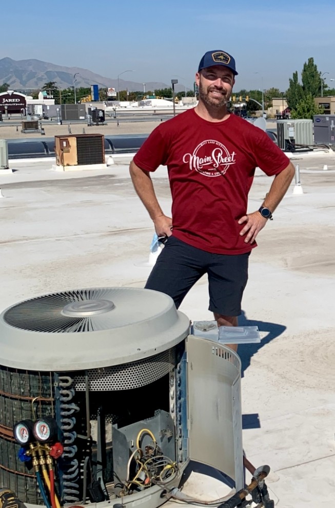 Owner wearing branded t-shirt repairing an AC unit